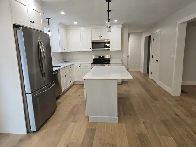 a kitchen with stainless steel appliances granite countertop a refrigerator a stove a sink dishwasher and a refrigerator with wooden floor