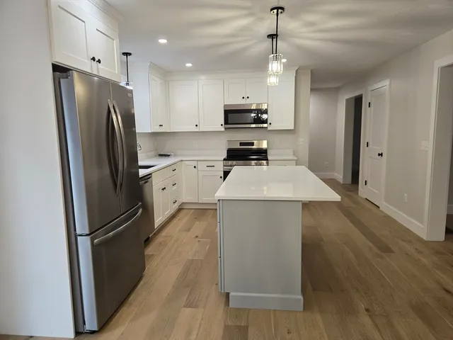 a kitchen with stainless steel appliances a refrigerator sink and wooden floor