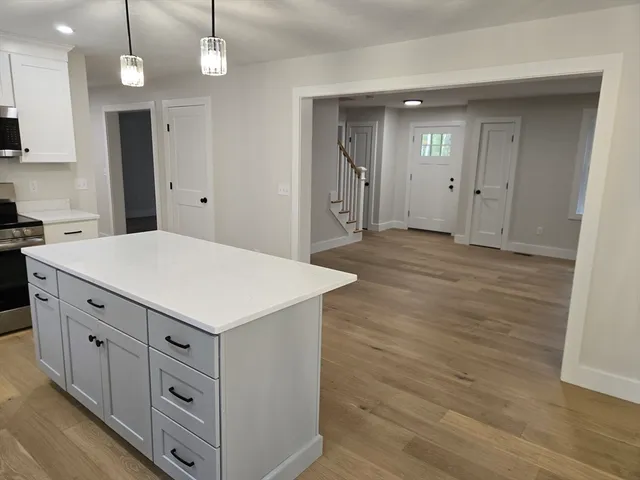 a kitchen with white cabinets and wooden floor