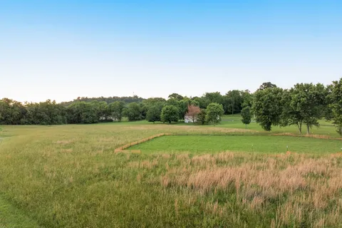 a view of field with grass and trees in the background