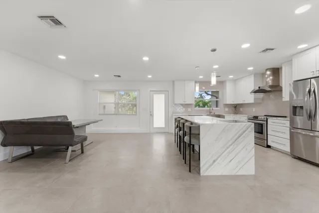 a kitchen with stainless steel appliances kitchen island granite countertop a refrigerator and a stove top oven