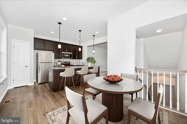 a kitchen with stainless steel appliances kitchen island a refrigerator and a wooden floor