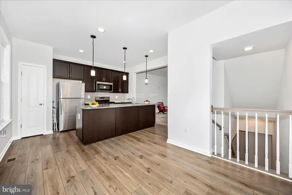 a kitchen with stainless steel appliances granite countertop a refrigerator a sink dishwasher a stove and a wooden floor