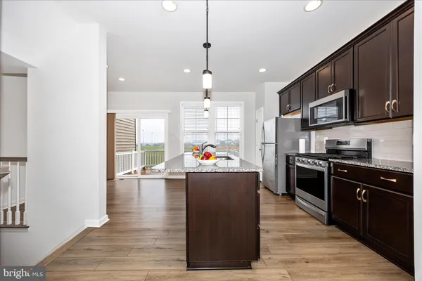 a kitchen with stainless steel appliances kitchen island granite countertop a stove a sink and a refrigerator