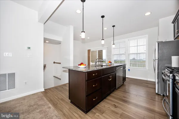 a kitchen with stainless steel appliances granite countertop a refrigerator a sink and wooden floor
