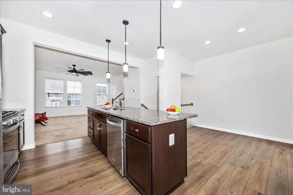 a kitchen with stainless steel appliances granite countertop a sink a stove and a wooden floors