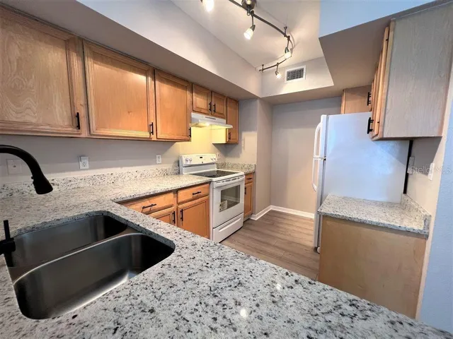 a kitchen with stainless steel appliances granite countertop a sink a stove and a refrigerator