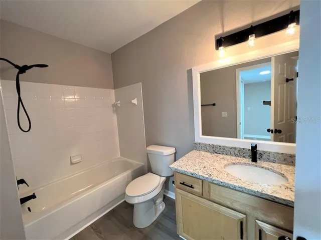 a bathroom with a granite countertop sink toilet and shower
