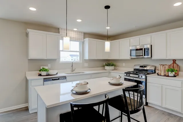 a kitchen with a dining table chairs white cabinets and appliances