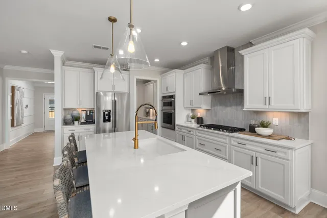 a kitchen with stainless steel appliances granite countertop a sink a stove a refrigerator cabinets and chairs