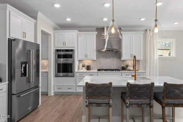 a kitchen with stainless steel appliances granite countertop a refrigerator a stove a sink a dining table and chairs