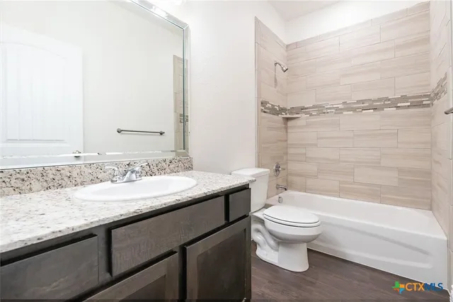 a bathroom with a granite countertop sink a toilet and shower
