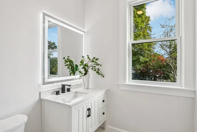 a bathroom with a granite countertop sink a large mirror and a window