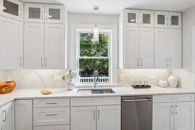 a kitchen with granite countertop a sink white cabinets and a window