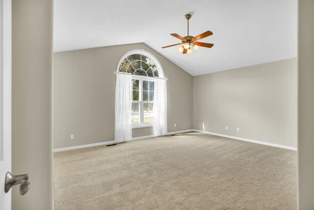 a view of a room with a ceiling fan and carpet