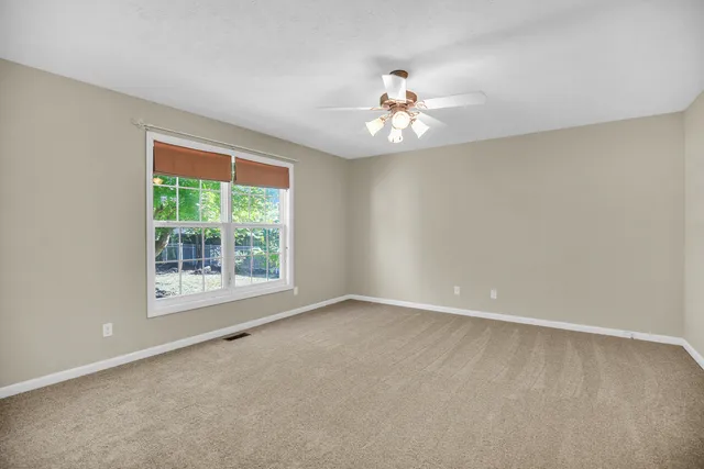 an empty room with windows and fan