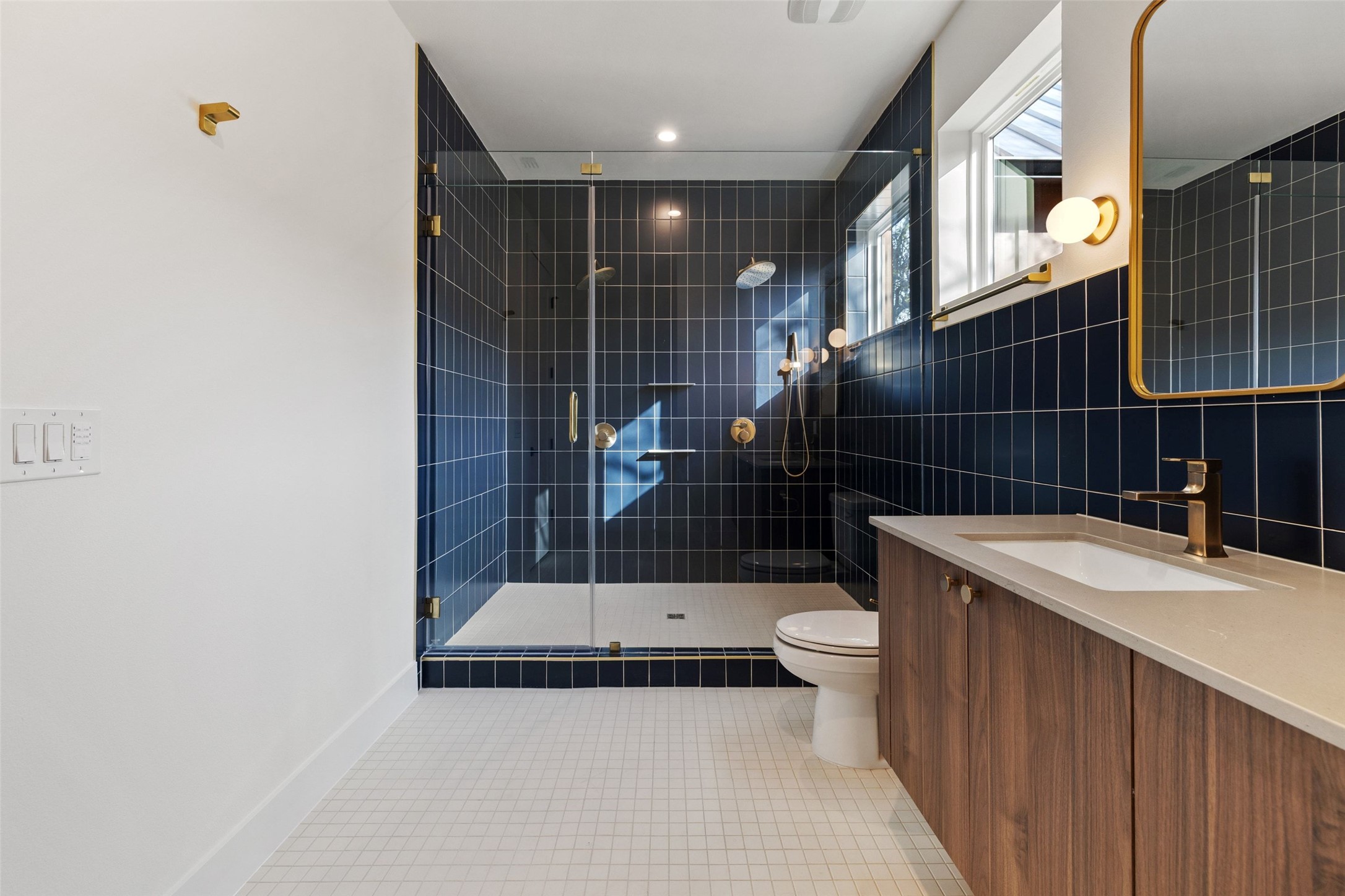 732 Springdale Road, Unit A Austin, TX 78702 - Photo 2 of 3 A striking bathroom features a spacious shower with sleek dark tiling and brass fixtures, complemented by a modern vanity.