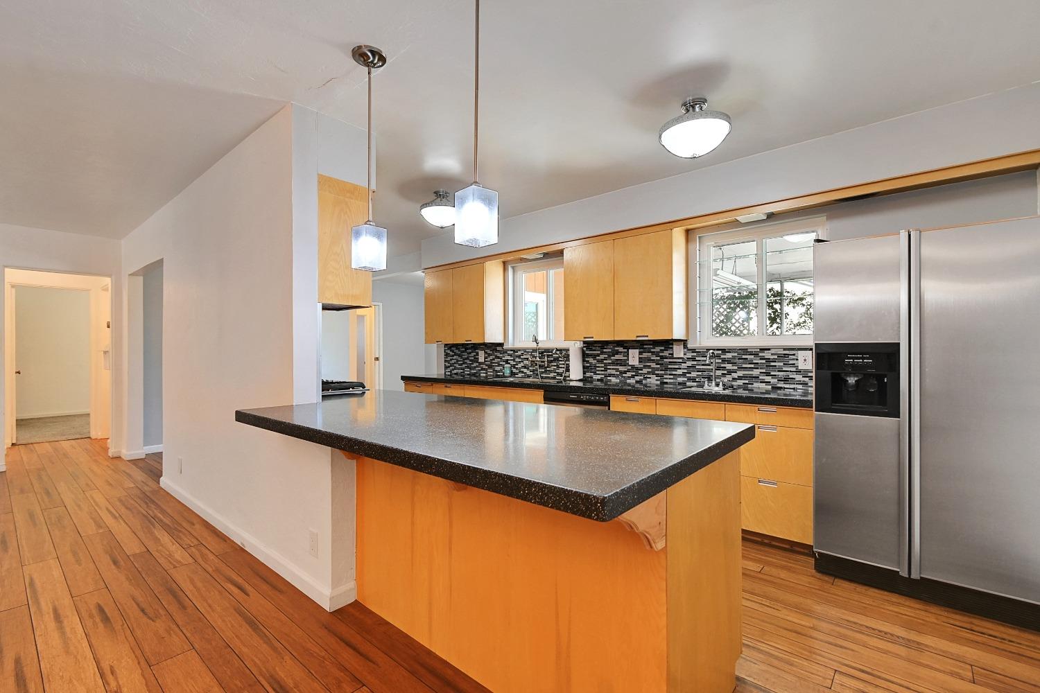 a kitchen with stainless steel appliances granite countertop a sink a refrigerator and a wooden floor