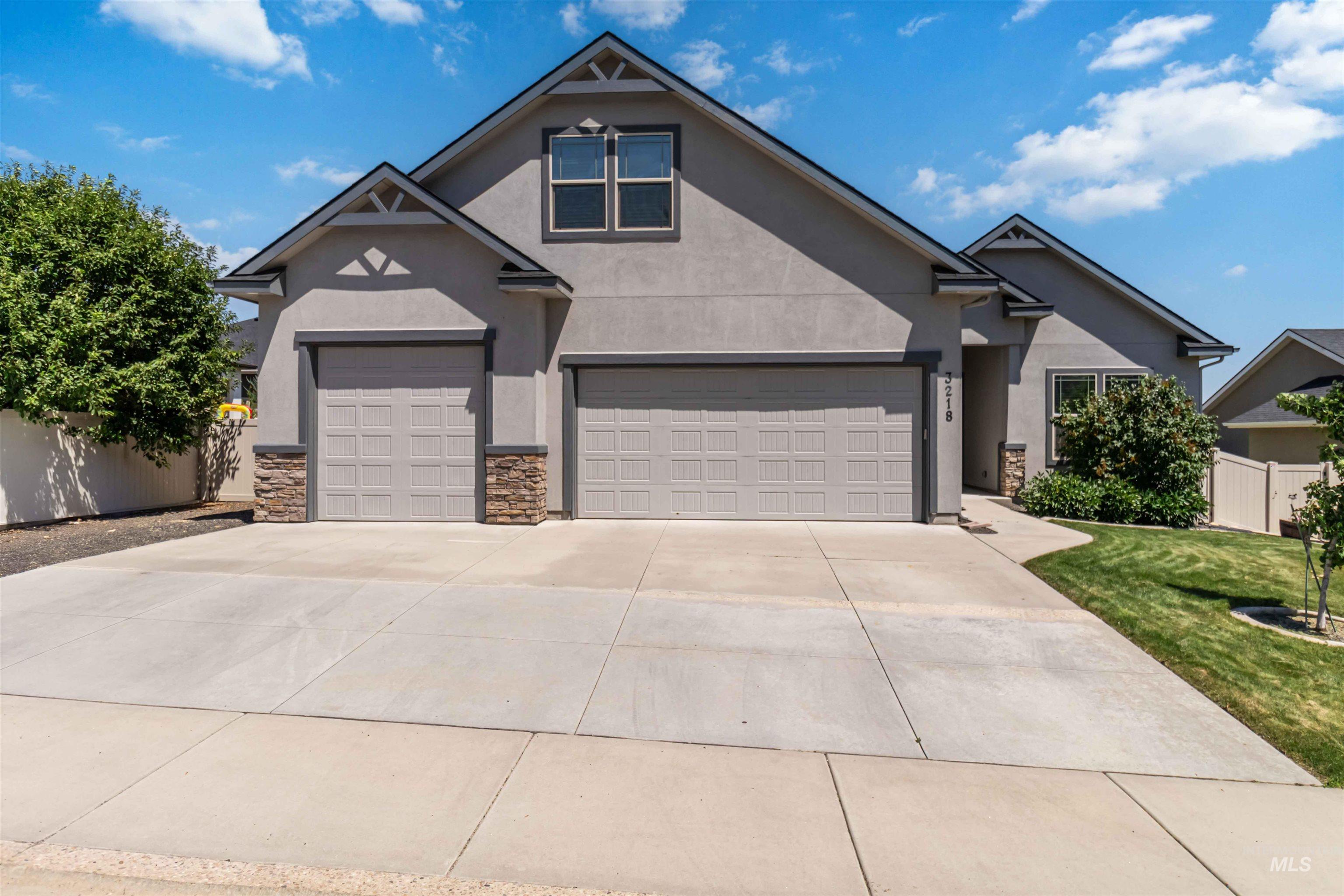 3218 North Cherry Laurel Way Star, ID 83669 - Photo 4 of 50 Stucco exterior featuring a panel garage door, a covered entry with a dark-paneled door, and stone accent pillars