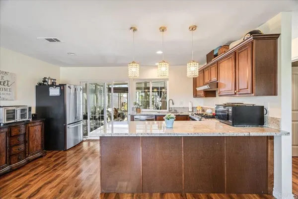 a kitchen with granite countertop a refrigerator stove top oven and sink