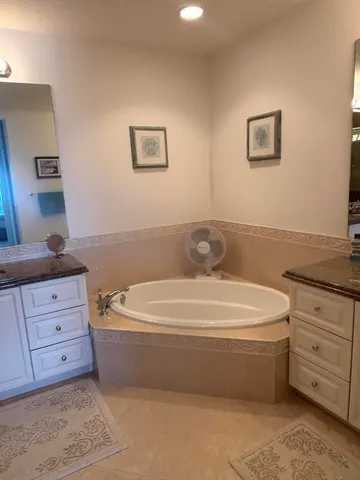 a spacious bathroom with a tub sink and mirror
