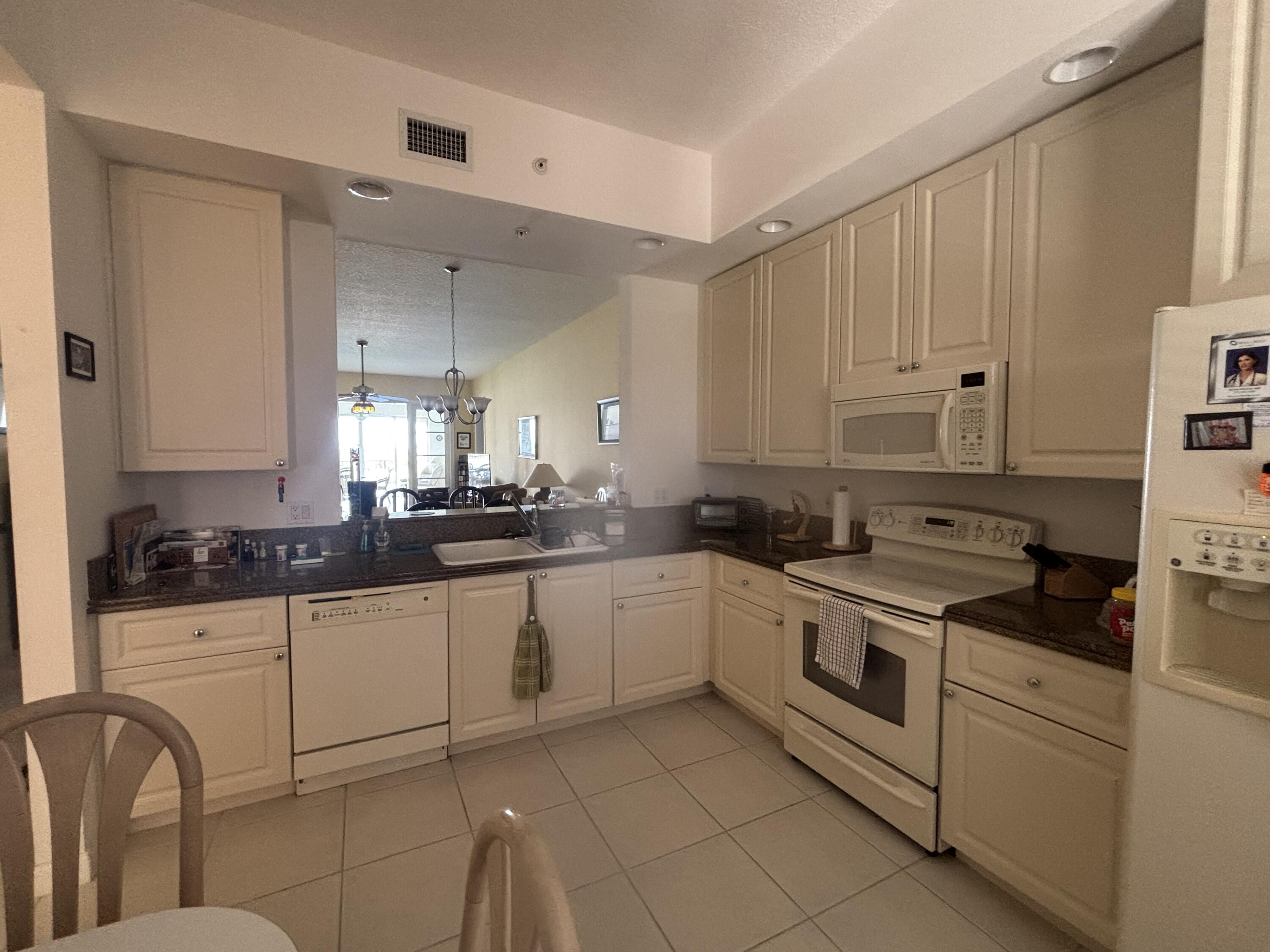 15 Harbour Isle Drive West, Unit PH 5 Fort Pierce, FL 34949 - Photo 2 of 20 a kitchen with granite countertop white cabinets and white appliances