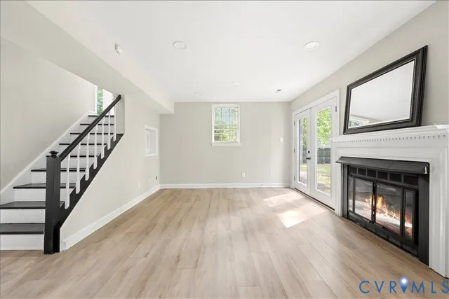a view of an empty room with wooden floor fireplace and a window