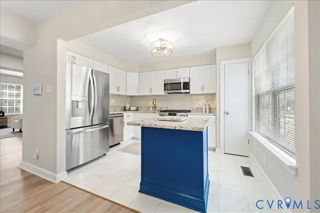 a kitchen with kitchen island a refrigerator a stove a sink and white cabinets with wooden floor