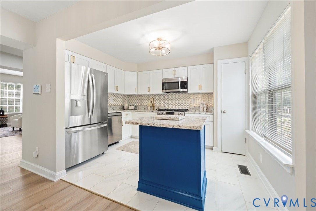 11601 Timberly Waye Henrico, VA 23238 - Photo 9 of 39 a kitchen with kitchen island a refrigerator a stove a sink and white cabinets with wooden floor