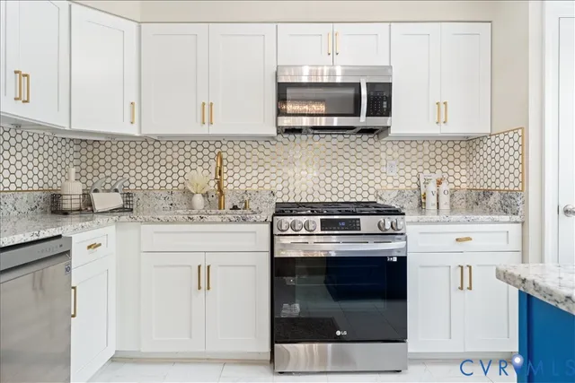 a kitchen with stainless steel appliances granite countertop white cabinets a microwave a sink and a counter