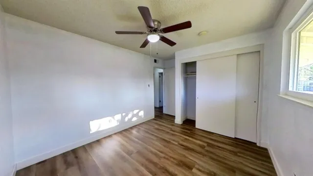 a view of empty room with wooden floor and fan