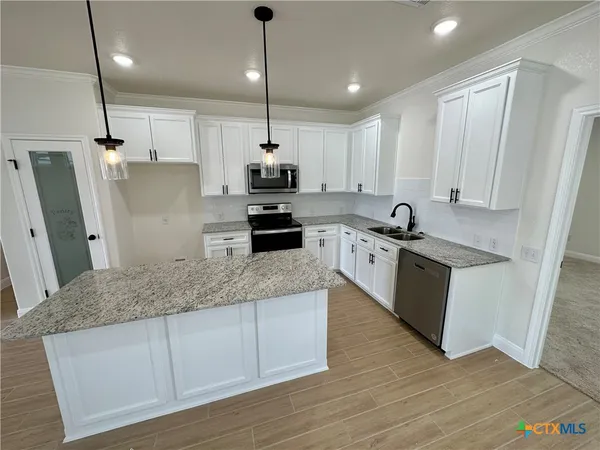 a kitchen with stainless steel appliances kitchen island a sink a stove a refrigerator and cabinets