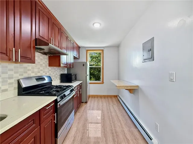 a kitchen with stainless steel appliances a stove a sink a refrigerator wooden floor and cabinets