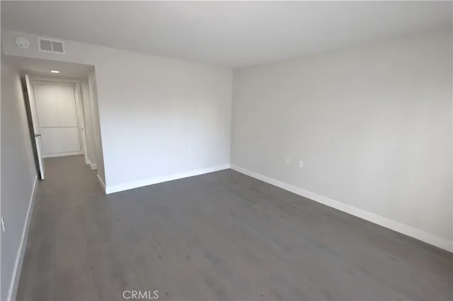 an empty room with wooden floor and mirror