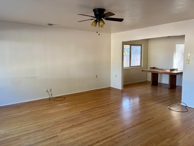 a view of a room with wooden floor and a ceiling fan