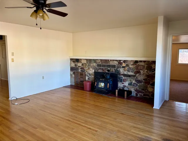 an empty room with wooden floor fireplace and windows