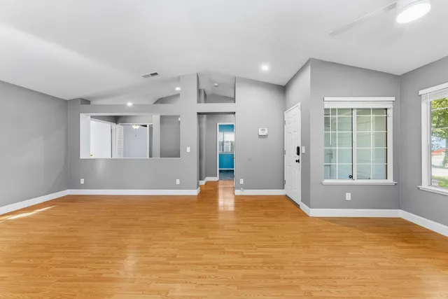 a view of an empty room with window and wooden floor