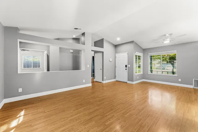 a view of empty room with wooden floor and windows