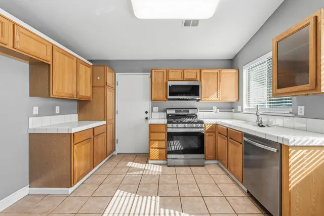 a kitchen with stainless steel appliances granite countertop a stove top oven a sink dishwasher and a refrigerator
