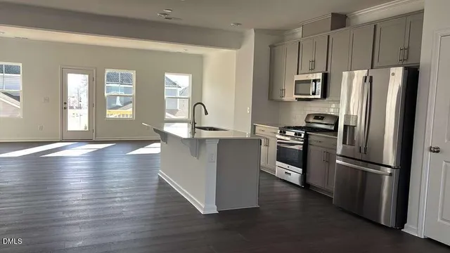 a kitchen with kitchen island a counter top space a sink and stainless steel appliances
