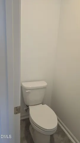 a white toilet sitting next to a white wall
