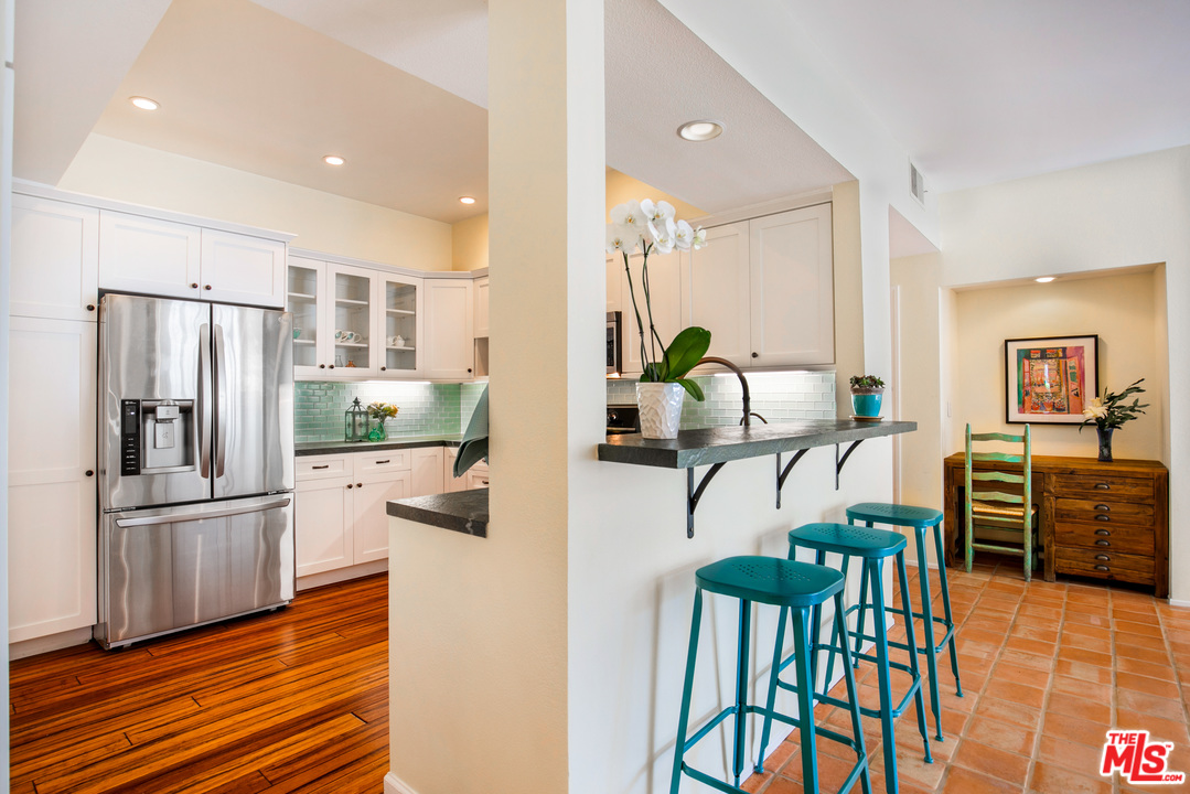 8180 Manitoba Street, Unit 124 Playa del Rey, CA 90293 - Photo 9 of 30 a kitchen with stainless steel appliances kitchen island granite countertop a refrigerator a stove top oven and a dining table with wooden floor