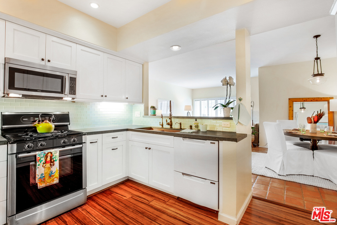 8180 Manitoba Street, Unit 124 Playa del Rey, CA 90293 - Photo 10 of 30 a kitchen with stainless steel appliances kitchen island granite countertop a stove a sink and a microwave