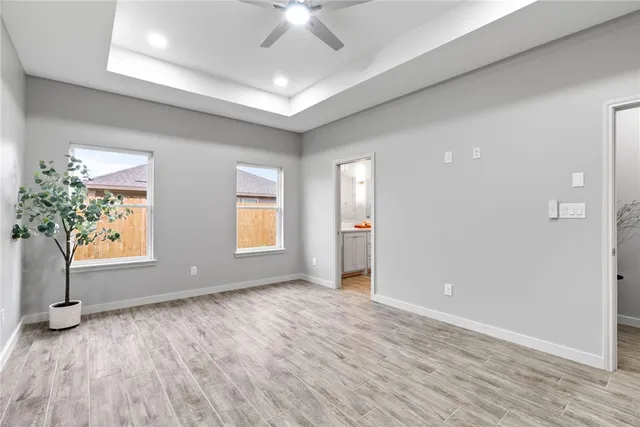 an empty room with windows & ceiling fan