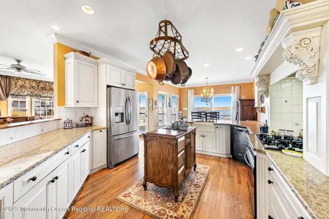 a kitchen with stainless steel appliances granite countertop a refrigerator a stove and a wooden floors