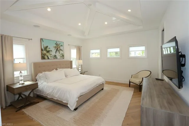 a bedroom with a bed a couch and a flat tv screen on dresser