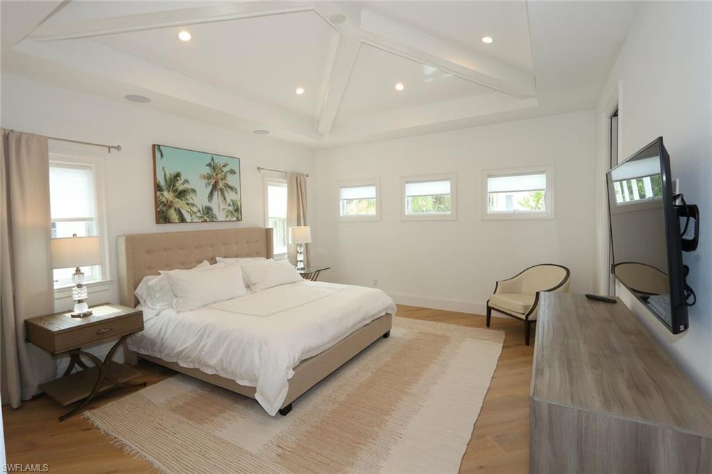 300 2nd Avenue North Naples, FL 34102 - Photo 23 of 41 a bedroom with a bed a couch and a flat tv screen on dresser