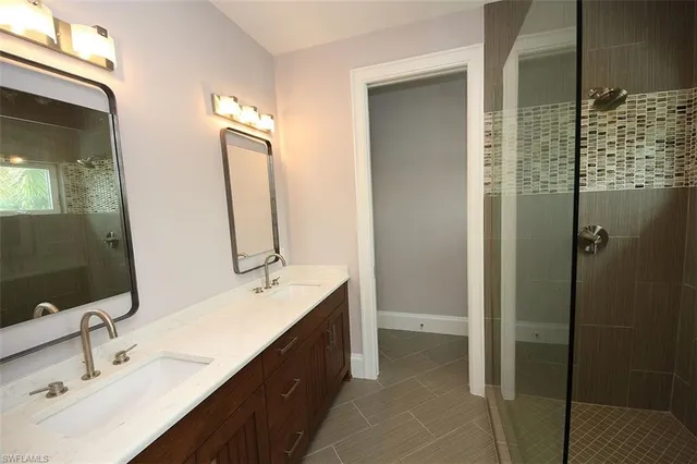 a bathroom with a double vanity sink mirror and shower