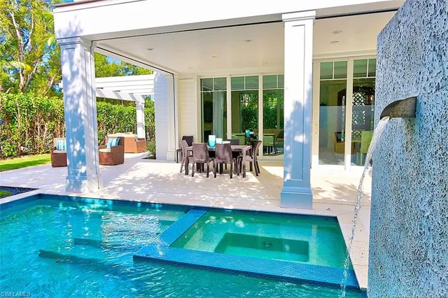 a view of a patio with table and chairs potted plants and floor to ceiling window