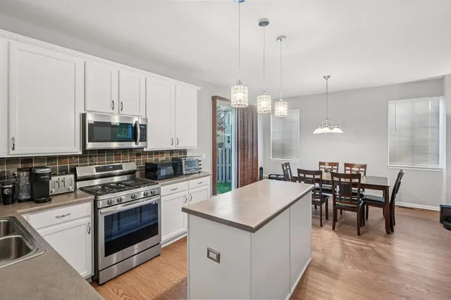 a large kitchen with kitchen island a table and chairs in it